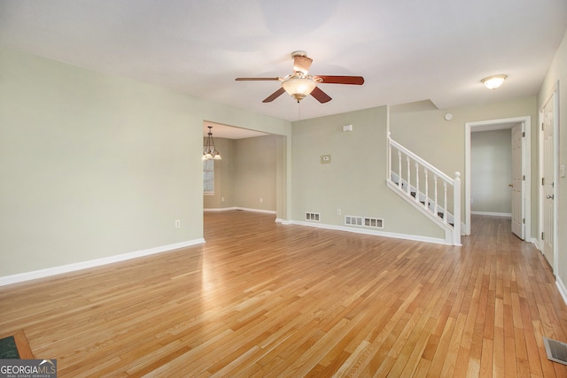 unfurnished living room featuring light hardwood / wood-style flooring and ceiling fan with notable chandelier