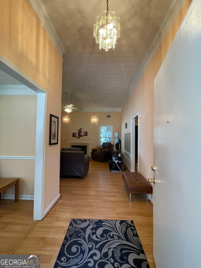 hallway featuring light hardwood / wood-style floors, ornamental molding, and a chandelier