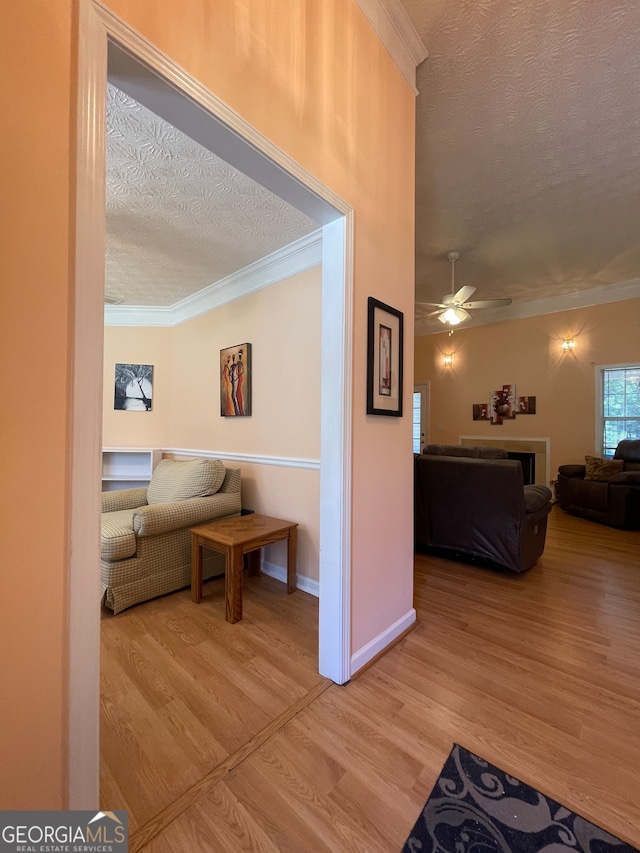 corridor featuring a textured ceiling, crown molding, and hardwood / wood-style flooring