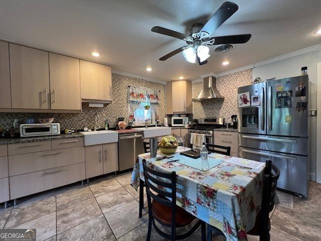 kitchen with sink, stainless steel appliances, wall chimney range hood, backsplash, and ornamental molding