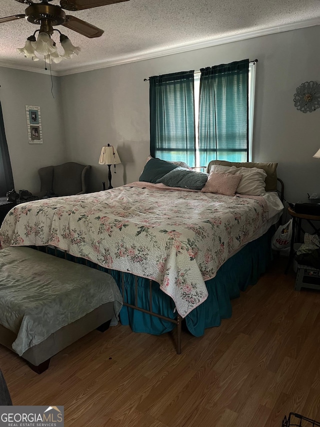 bedroom with ceiling fan, crown molding, wood-type flooring, and a textured ceiling