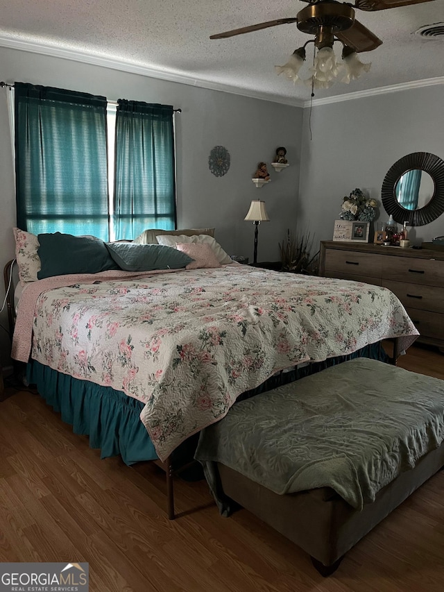 bedroom with a textured ceiling, hardwood / wood-style flooring, ceiling fan, and ornamental molding