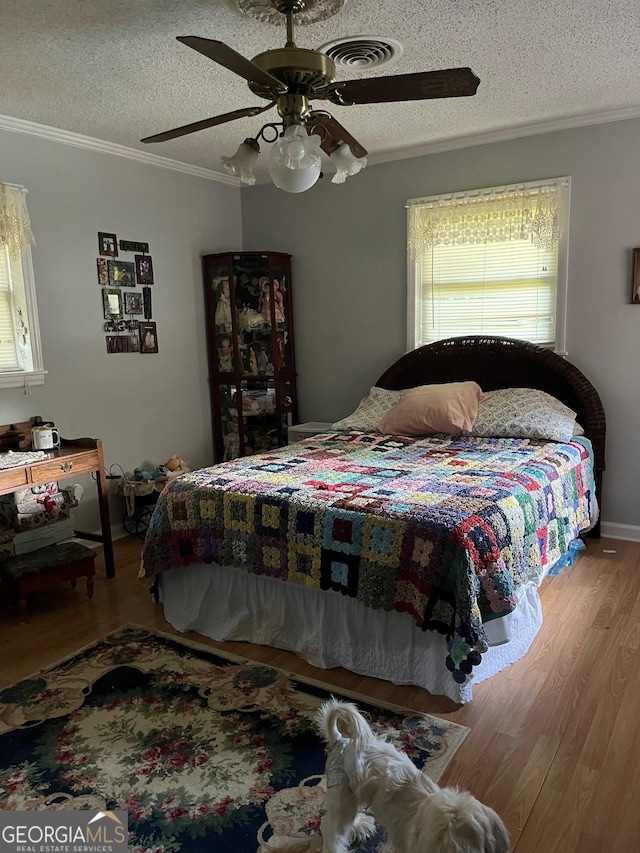 bedroom featuring hardwood / wood-style floors, ceiling fan, crown molding, and a textured ceiling