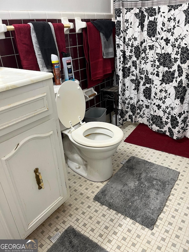 bathroom with vanity, toilet, and tile walls