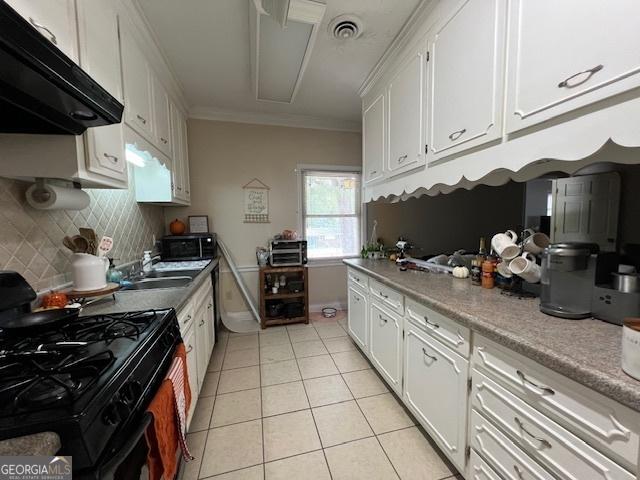 kitchen with black appliances, sink, light tile patterned floors, ornamental molding, and white cabinetry