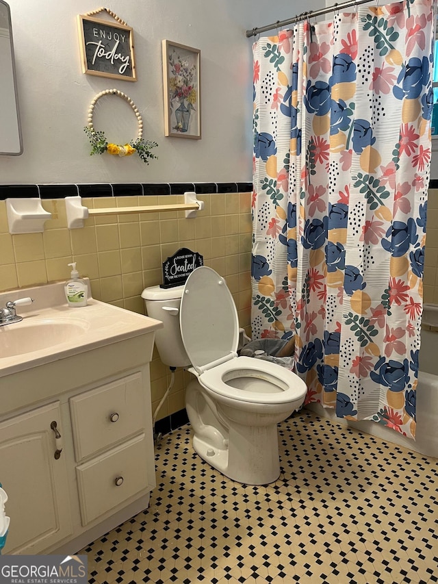 bathroom featuring tile patterned floors, vanity, tile walls, and toilet