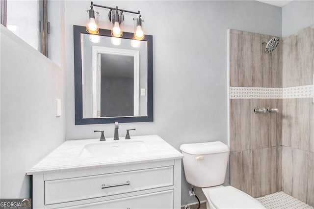 bathroom featuring a tile shower, vanity, and toilet