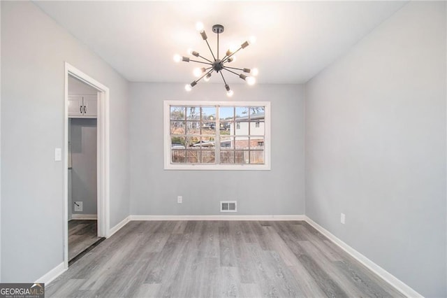 unfurnished room featuring light hardwood / wood-style floors and an inviting chandelier