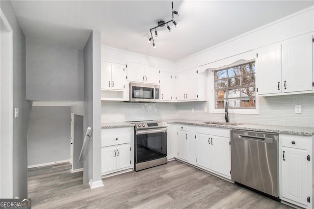 kitchen with white cabinets, appliances with stainless steel finishes, light wood-type flooring, and sink