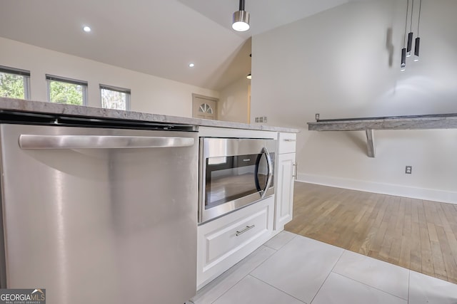 kitchen featuring light hardwood / wood-style floors, white cabinets, vaulted ceiling, stainless steel appliances, and decorative light fixtures