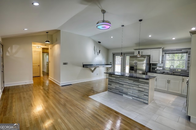 kitchen featuring light hardwood / wood-style floors, stainless steel refrigerator with ice dispenser, lofted ceiling, and sink