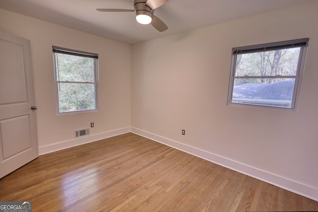 empty room with wood-type flooring, ceiling fan, and a wealth of natural light