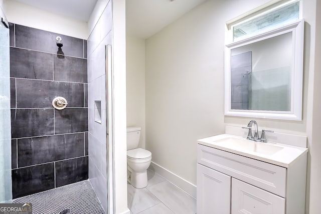 bathroom featuring a tile shower, tile patterned flooring, vanity, and toilet