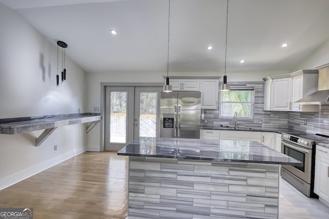 kitchen with sink, white cabinets, vaulted ceiling, appliances with stainless steel finishes, and decorative light fixtures