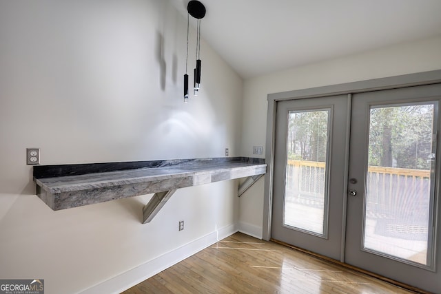 doorway featuring light wood-type flooring, vaulted ceiling, and french doors