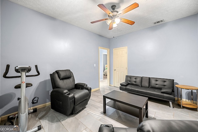 living room with a textured ceiling and ceiling fan