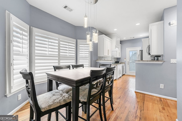 dining area with light wood-type flooring, sink, and a healthy amount of sunlight