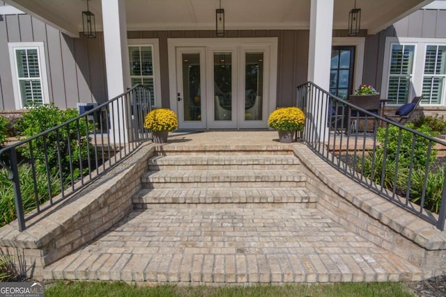 view of exterior entry with covered porch, french doors, and board and batten siding