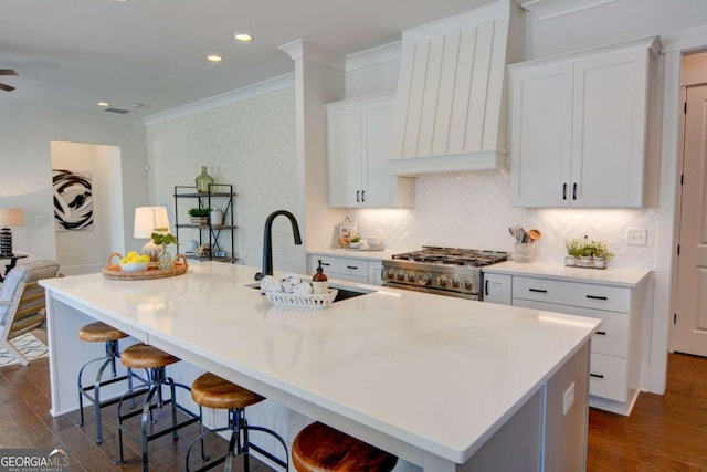 kitchen with stainless steel range, dark wood-style floors, custom range hood, ornamental molding, and a sink