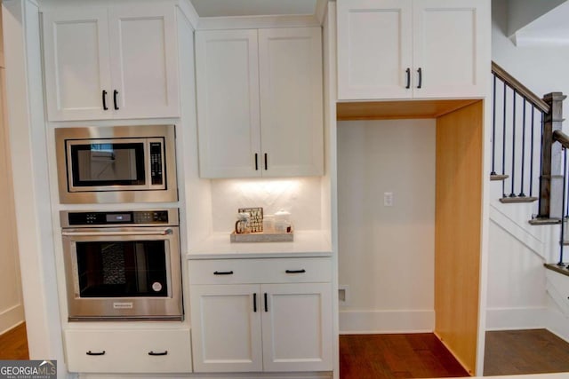 kitchen with appliances with stainless steel finishes, white cabinets, and dark wood-style flooring