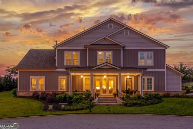 view of front of house featuring a standing seam roof, brick siding, a front lawn, and board and batten siding