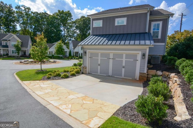 view of front of home featuring board and batten siding, a standing seam roof, a garage, cooling unit, and driveway