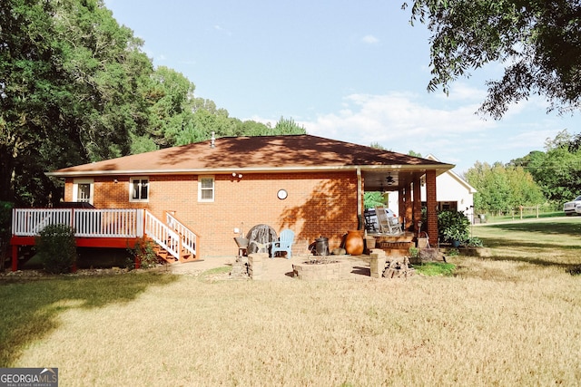 back of house featuring a yard, a deck, and an outdoor fire pit