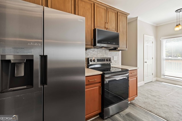 kitchen with light hardwood / wood-style floors, decorative light fixtures, decorative backsplash, ornamental molding, and appliances with stainless steel finishes