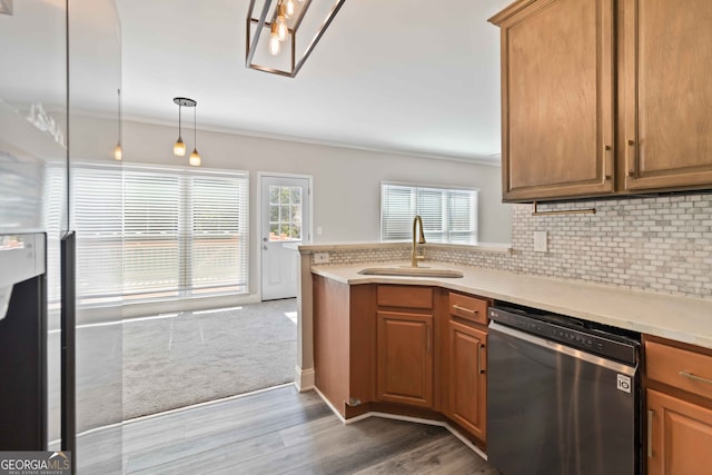 kitchen featuring hardwood / wood-style flooring, hanging light fixtures, crown molding, and stainless steel dishwasher