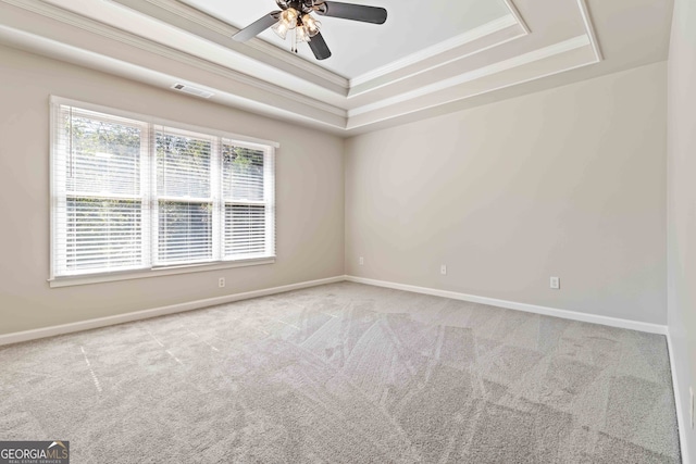 spare room featuring ornamental molding, ceiling fan, a tray ceiling, and light colored carpet