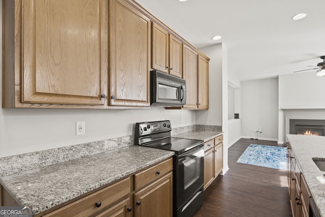 kitchen with ceiling fan, light stone countertops, dark hardwood / wood-style floors, and black appliances