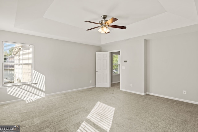 carpeted empty room featuring a raised ceiling and ceiling fan