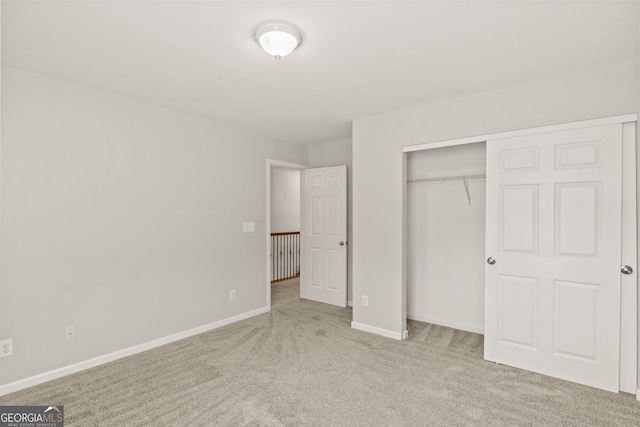 unfurnished bedroom with light colored carpet and a closet