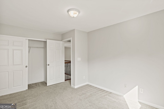 unfurnished bedroom with light colored carpet and a closet