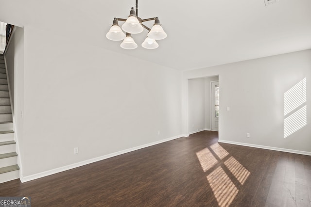 spare room with an inviting chandelier and dark hardwood / wood-style flooring