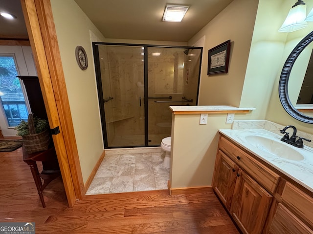 bathroom with toilet, vanity, hardwood / wood-style floors, and a shower with shower door