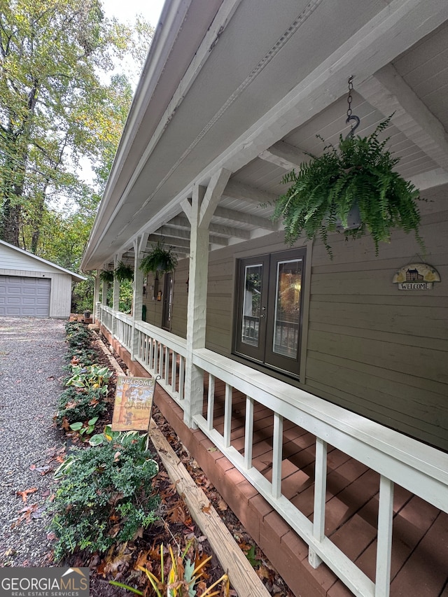 view of side of home featuring a garage, an outdoor structure, and a porch