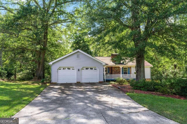 single story home with a porch, a garage, and a front yard