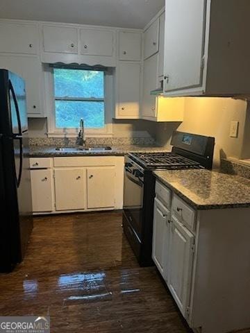 kitchen with dark wood-type flooring, sink, black appliances, dark stone countertops, and white cabinets