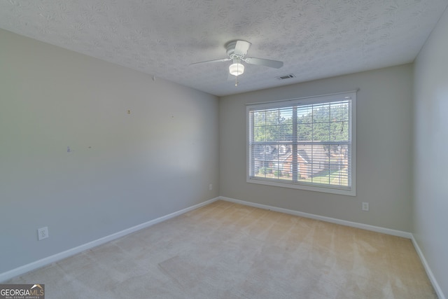 carpeted empty room with ceiling fan and a textured ceiling