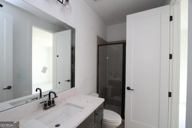 bathroom featuring an enclosed shower, vanity, and toilet