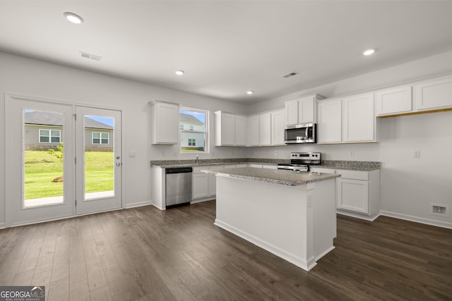 kitchen with appliances with stainless steel finishes, white cabinetry, a center island, and plenty of natural light