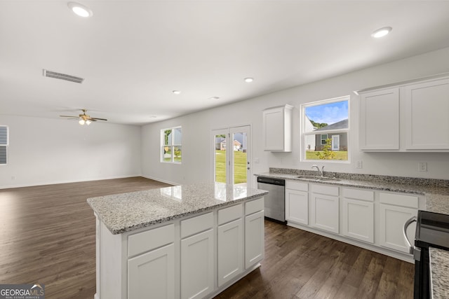 kitchen featuring light stone counters, white cabinets, dark wood-type flooring, stainless steel appliances, and a center island