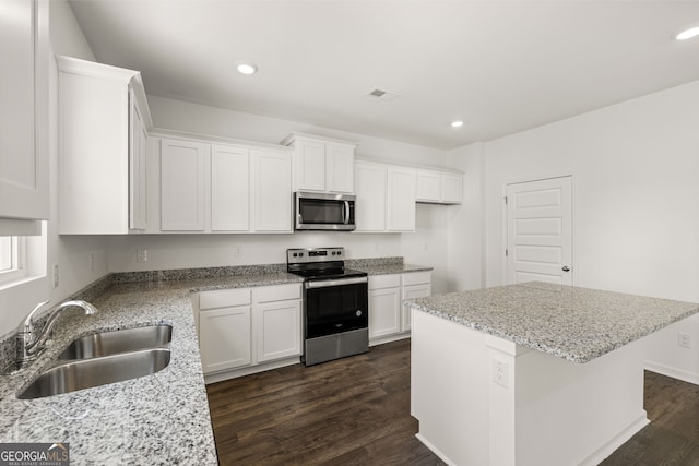 kitchen with sink, dark wood-type flooring, white cabinetry, appliances with stainless steel finishes, and a center island