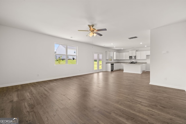 unfurnished living room featuring ceiling fan and dark wood-type flooring