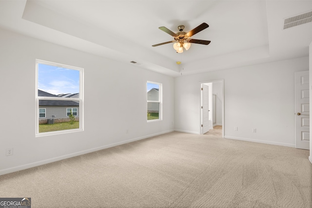 spare room featuring a tray ceiling, ceiling fan, and light colored carpet