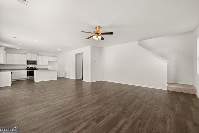 unfurnished living room featuring ceiling fan and dark wood-type flooring