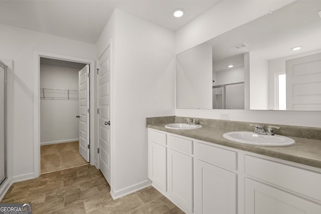 bathroom featuring a shower with door and vanity