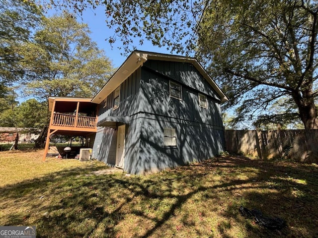 view of property exterior with a wooden deck, a yard, and cooling unit