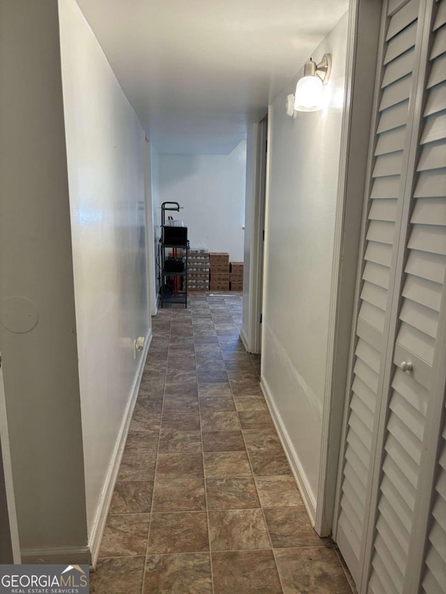 corridor with stone finish flooring and baseboards